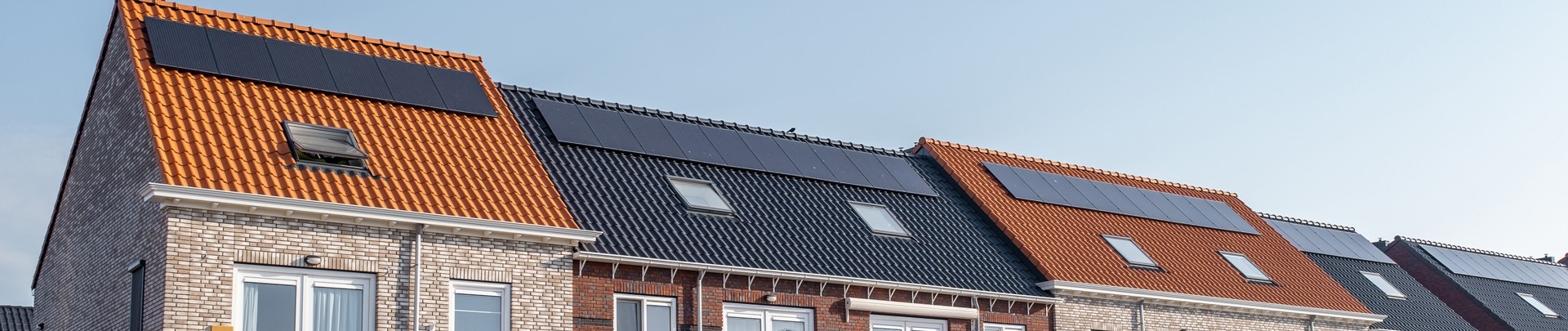 Nieuw gebouwde huizen met zonnepanelen op het dak met op de achtergrond een mooie blauwe lucht